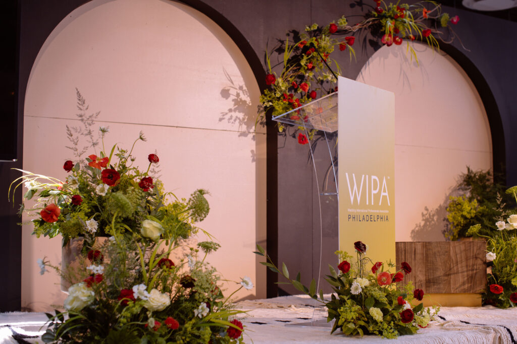 Red, white, and green florals decorating a stage for WIPA's corporate event.