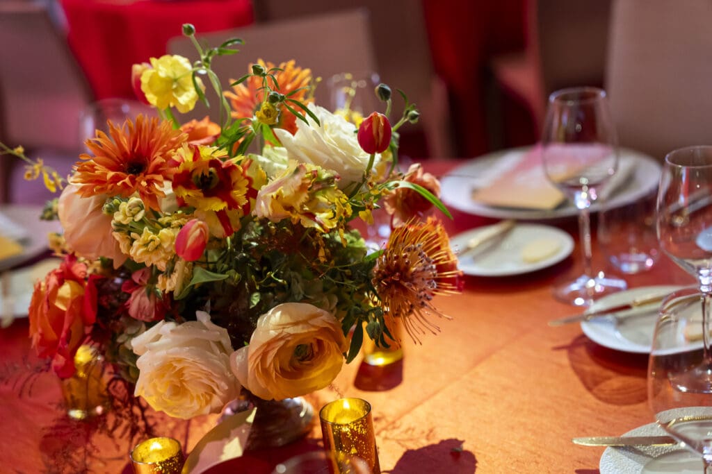 Fiery red and orange centerpiece florals at a corporate dinner party.