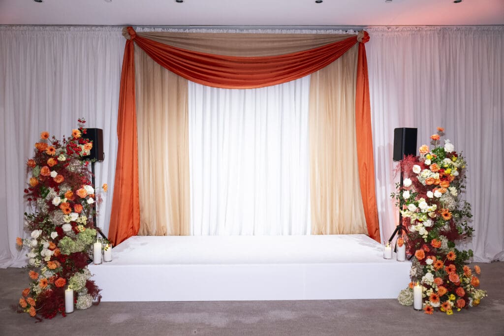 Bright orange and red floral accents for a corporate stage.