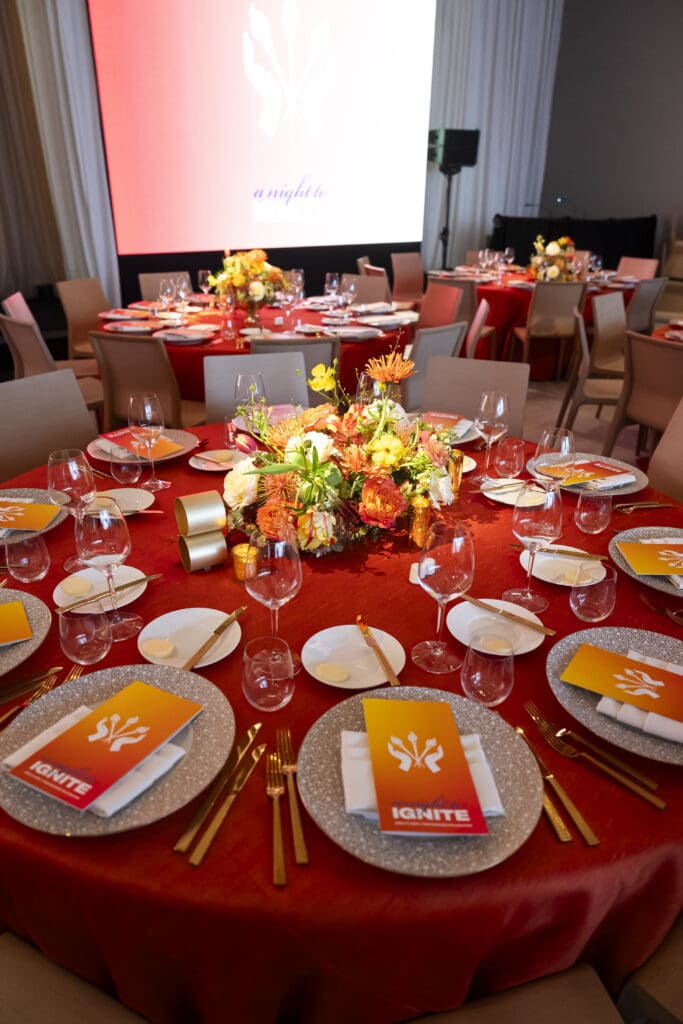 Red and orange table decor and florals for a corporate dinner event.