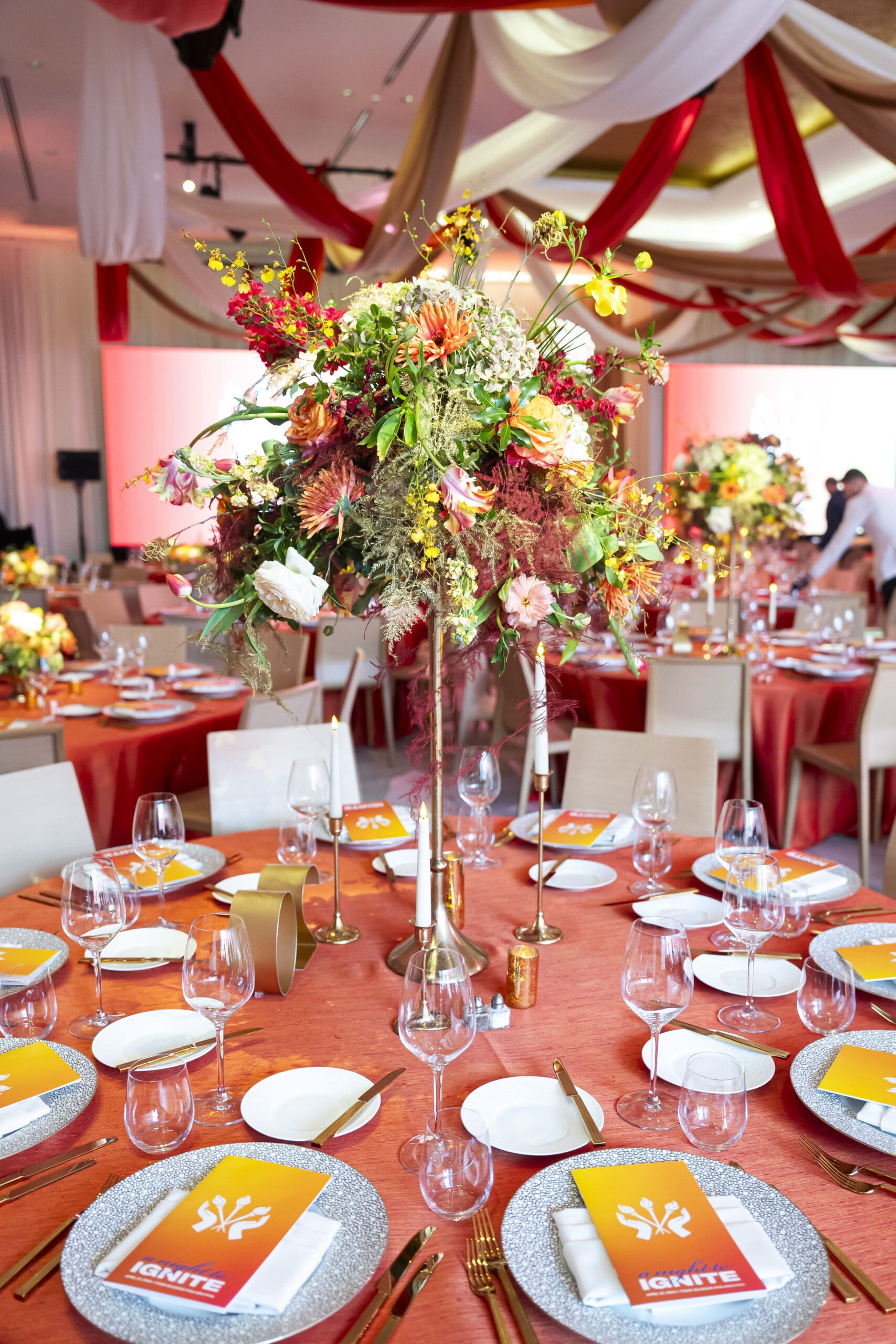 A bright red and orang floral centerpiece to complete this corporate event's tablescape.