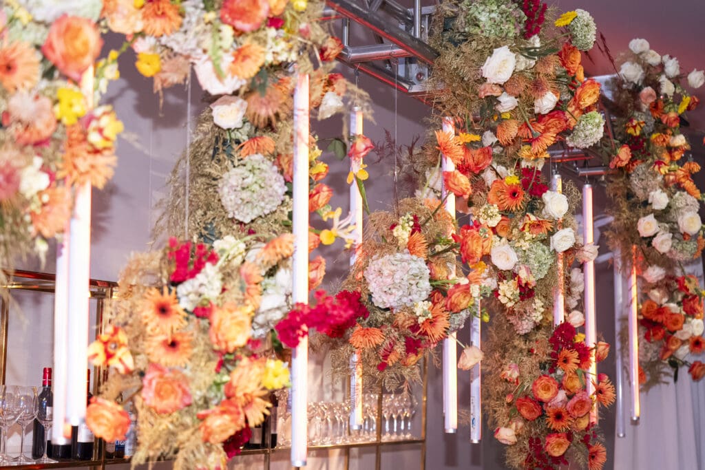 Hanging fall floral arrangements behind the bar, creating a stunning seasonal backdrop for the event.