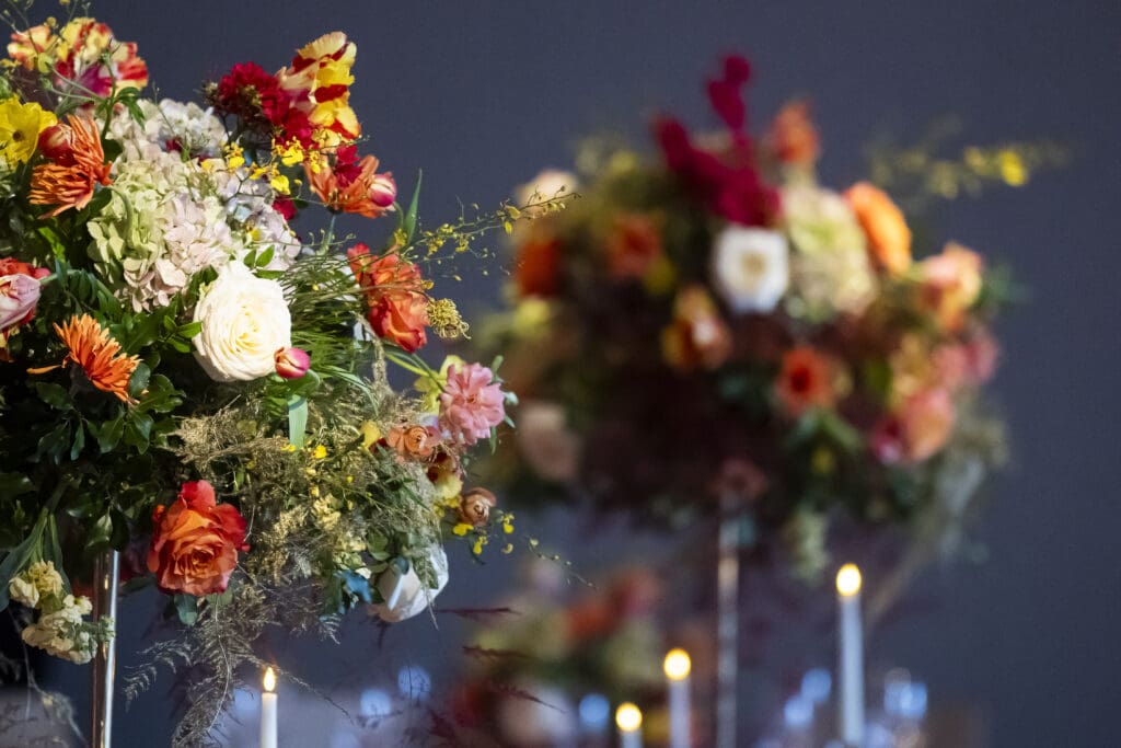 Up-close shot of a fall-inspired centerpiece adorned with autumn florals and lit candles, creating a warm ambiance.