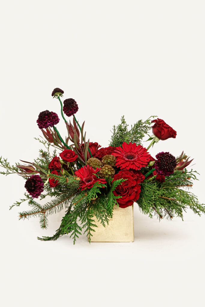 Handcrafted arrangement with fresh evergreens, berries, and a touch of sparkle, designed by Philadelphia's premier floral shop for the holiday season.