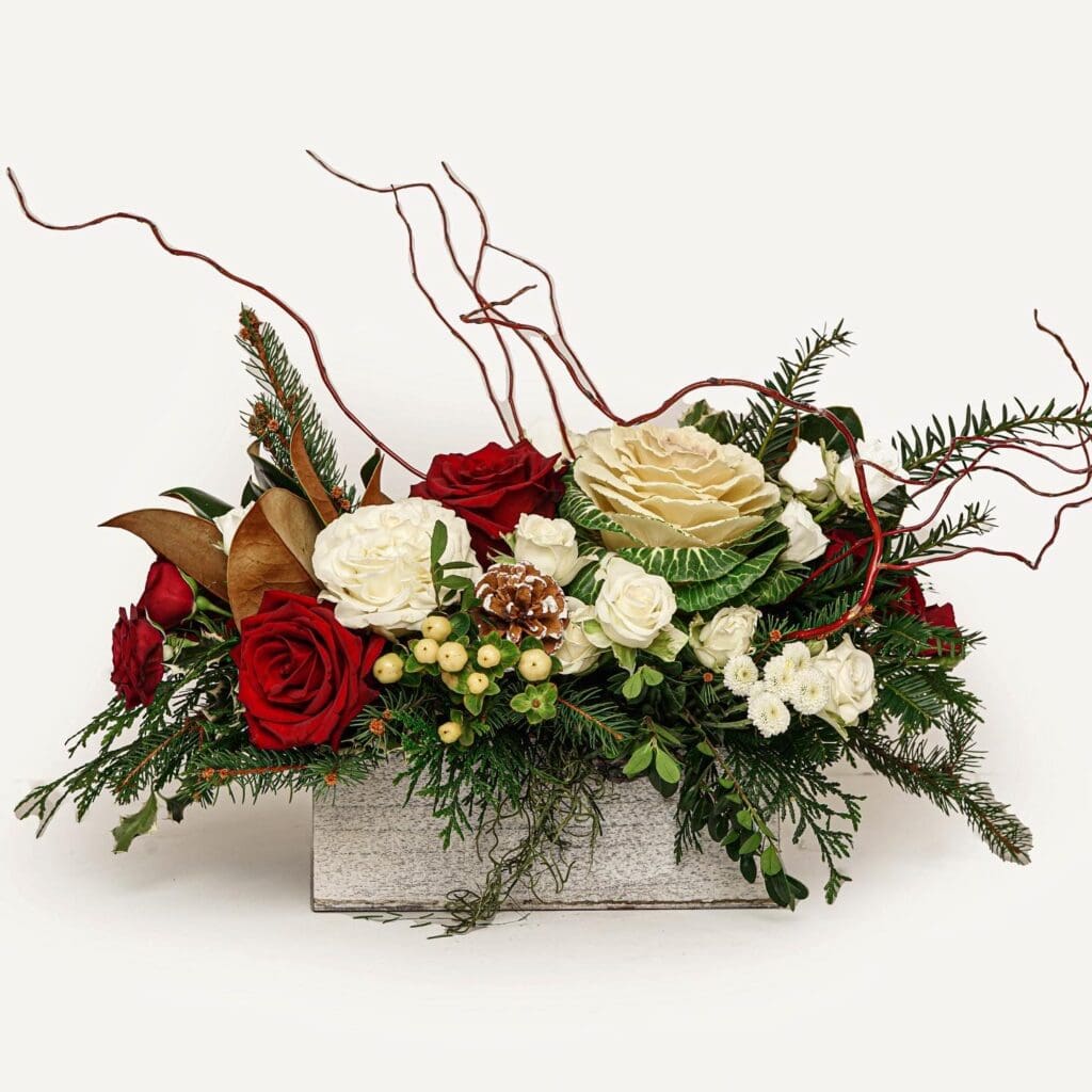 Elegant holiday floral arrangement featuring rich red roses, winter greenery, and gold accents, crafted by 7Blooms, a bespoke floral shop in Philadelphia.